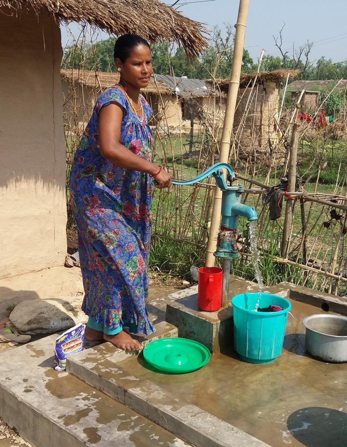 A women in Nepal filling up a buck of water at a well.