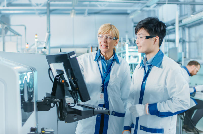 A photo of a male and female scientist reviewing data on a computer screen in a lab.