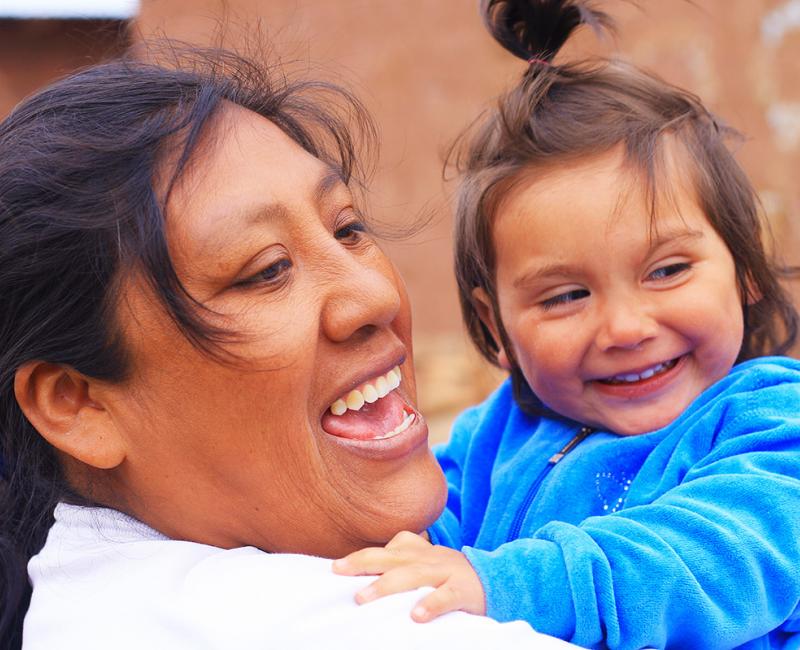 A close-up photo of a smiling mother and her smiling child.