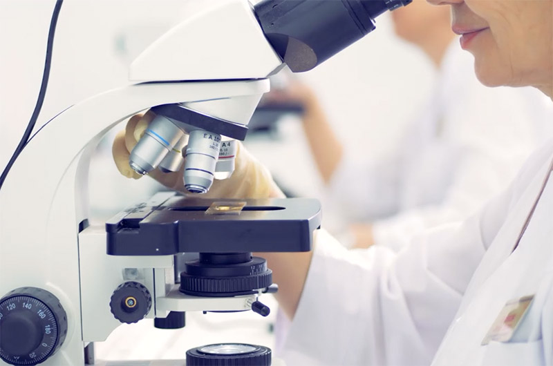 Lab technician looking through microscope